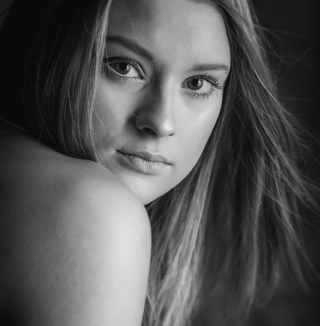 Studijski portret mlade žene s kovrčavom kosom koja se smiješi